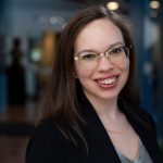 Alyssa Webb, a woman with glasses and long brown hair, smiles at the camera.