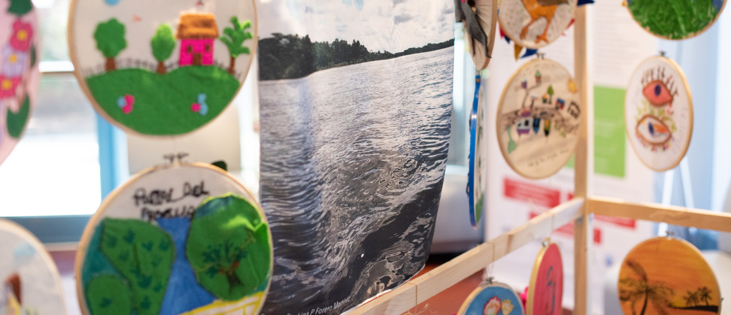 Embroidery and fabrics hang from displays during the Casa Común (Communal House) art project